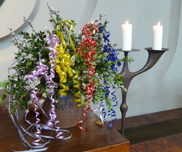 Fotos zeigt kleinen Kerzenständer mit Osterschmuck auf dem Altar